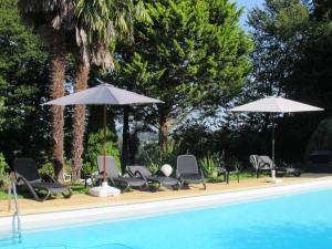 - un groupe de chaises longues et de parasols à côté de la piscine dans l'établissement Logis Deshors-Foujanet, à Chamboulive