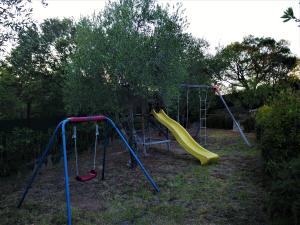 a playground with two swings and a slide at Résidence Villa Smeralda in Telti