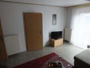 Sala de estar con puerta y TV en Ferienwohnung Baumberge, en Nottuln
