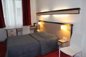 シャルルヴィル・メジエールにあるHôtel de la Meuseのベッドルーム1室(ベッド1台、テーブル、椅子付)