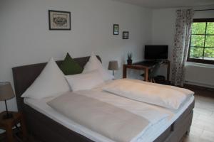 Schlafzimmer mit einem Bett mit weißer Bettwäsche und einem Schreibtisch in der Unterkunft Gästezimmer Gier in Dahlem