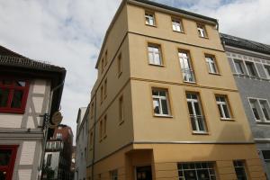 a tall yellow building with windows on a street at FeWo Schweriner Altstadt in Schwerin