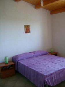 ノート・マリーナにあるVilla Flaviaの紫色のベッドと木製の天井が備わるベッドルーム1室が備わります。