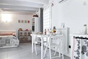 a white kitchen with a table and white chairs at Casetta Bianca B&B in San Giovanni Lupatoto