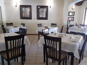 a restaurant with tables and chairs with white tablecloths at Marlot Guest House in Polokwane