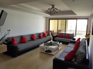 - un salon avec des canapés et des oreillers rouges dans l'établissement Plage Des Nations Golf Resort, à Sidi Bouqnadel