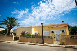 una casa amarilla con una valla y una calle en Casa Heidi, en Cala Santanyi