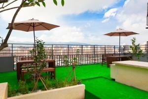 a balcony with tables and umbrellas and green grass at Hotel East Taipei in Taipei