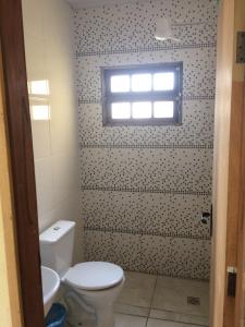 une salle de bain avec toilettes et fenêtre dans l'établissement Pousada e Restaurante do Porto, à São João Batista do Glória