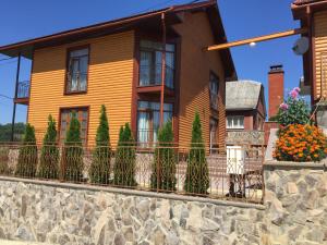a house with a stone wall and a fence at Mini hotel Solnce Karpat in Polyana