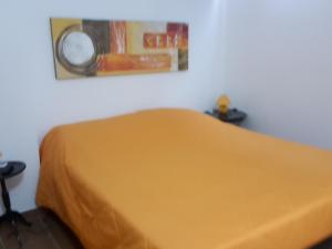 - une chambre dotée d'un lit jaune avec une photo sur le mur dans l'établissement Palazzo Graziano, à Terrasini