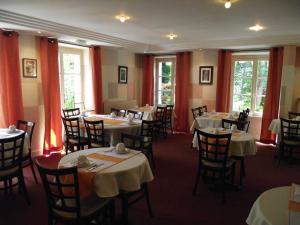 uma sala de jantar com mesas e cadeiras e cortinas vermelhas em Cit'Hotel Avallon Vauban em Avallon