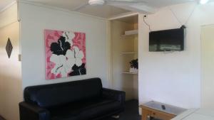 a living room with a black leather chair and a flat screen tv at Samoa Home in Vaitele