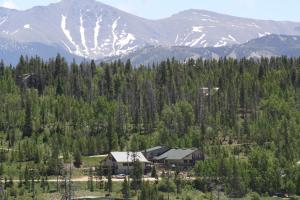 a house in the middle of a forest with mountains at Hideaway Mountain Lodge in Fraser