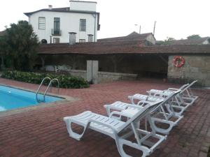 a row of white lounge chairs next to a pool at Estrebuela House in Paredes