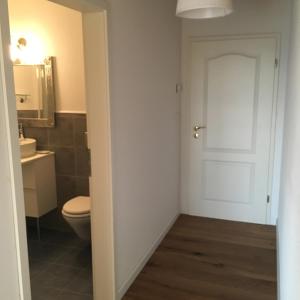 a bathroom with a toilet and a white door at Zimmer mit Bad und Balkon in Widen