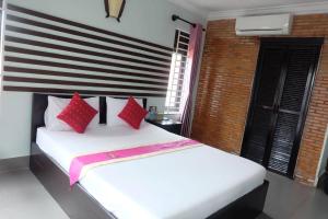 a bedroom with a white bed with red pillows at VIBOLA Guesthouse in Kampot