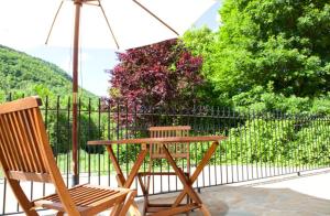 een houten tafel en twee stoelen met een parasol bij Apartahotel Castejón de Sos in Castejón de Sos