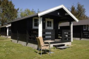 a black cabin with a table and chairs in front of it at Løkken Klit Camping & Cottage Village in Løkken