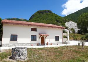 a small white house with mountains in the background at B&B Masseria Cozzi in Lauria Inferiore