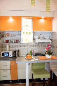 eine Küche mit orangefarbenen und weißen Schränken und einem Tisch in der Unterkunft Apartman Lena in Vrnjačka Banja