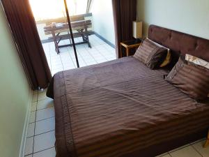 a large bed in a bedroom with a balcony at Dumela Margate Flat 21 in Margate