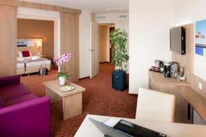 a hotel room with a bed and a living room at Mercure Hotel Hamburg am Volkspark in Hamburg