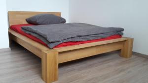 una cama de plataforma de madera con una manta gris. en Schwalbennest, en Fürth
