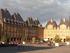 un grand bâtiment avec des tables et des chaises devant lui dans l'établissement Hôtel de la Meuse, à Charleville-Mézières