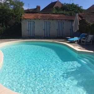 une grande piscine bleue avec deux chaises et une maison dans l'établissement Chambres d'hôtes et Roulotte Au Bonheur Du Parc, à Le Breuil