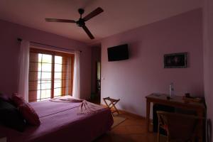 a bedroom with a bed with a ceiling fan and a window at Kira's Boutique Hotel in Mindelo