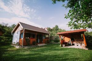 een klein huis met een veranda en een schuur bij Bosnyák Panzió in Odorheiu Secuiesc