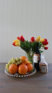 a plate of fruit and flowers and a bottle of wine at Gina's garden house in Amsterdam