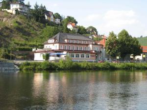 a house on a hill next to a body of water at Hotel V Pivovaře Davle in Davle