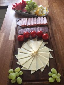 a wooden cutting board with cheese and meats and grapes at BB-Vesterskov in Nykøbing Falster