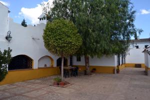 einen Innenhof mit einem Tisch und einem Baum vor einem Gebäude in der Unterkunft Cortijo Jabonero in Mollina