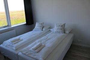 a white bed with two pillows and a window at Ocean Beach Apartments in Stokkseyri