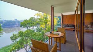 a room with a table and chairs and a view of a river at Anantara Chiang Mai Resort in Chiang Mai
