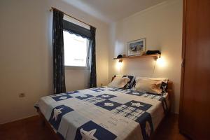 een slaapkamer met een bed met een blauwe en witte deken bij Apartments Villa Dolmar in Vodice