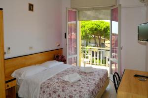 1 dormitorio con 1 cama y puerta a un balcón en Hotel Levante, en Cervia