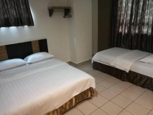 a bedroom with two beds and a window at Hotel Traveller in Kota Kinabalu