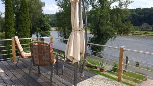 einen Regenschirm und einen Stuhl auf einem Deck neben einem Fluss in der Unterkunft Ferienwohnung Oberposta in Pirna