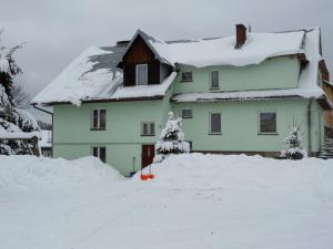 a house covered in snow in front of it at Dom Gościnny Kama in Tylicz
