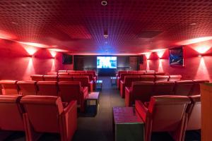 a cinema room with red chairs and a tv at Whatley Manor in Malmesbury