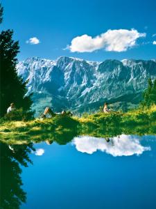 a group of people sitting on a hill with a view of mountains at Apartment Zaglau in Sankt Johann im Pongau