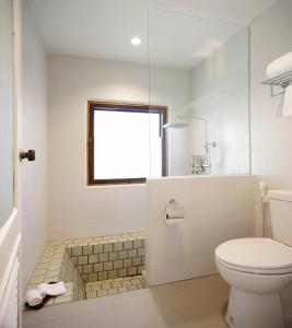 a white toilet sitting next to a bath tub in a bathroom at Malibu Koh Samui Resort & Beach Club - SHA Extra Plus in Chaweng