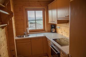 kuchnia ze zlewozmywakiem i oknem w drewnianym domku w obiekcie Ferienhaus Krassnig w mieście Turracher Hohe