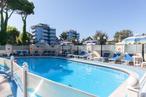 una gran piscina con tumbonas y sombrillas en Hotel Levante, en Cervia