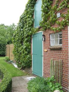 ein Backsteinhaus mit grüner Tür und Efeu in der Unterkunft 't Zwaluwennest in Exloo