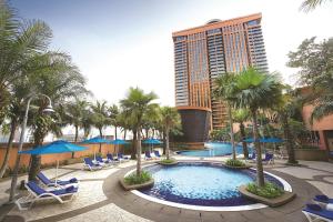 een zwembad met stoelen en palmbomen en een hoog gebouw bij Berjaya Times Square Hotel, Kuala Lumpur in Kuala Lumpur